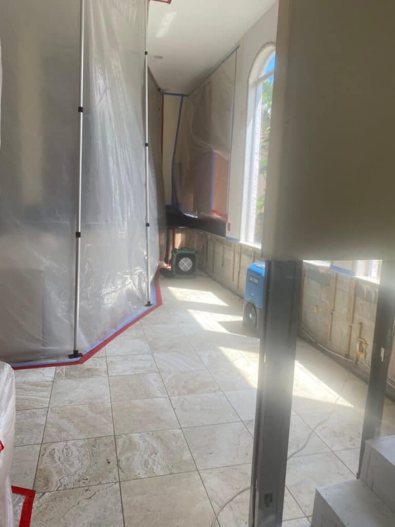 Containment barriers along a tiled hallway during remediation