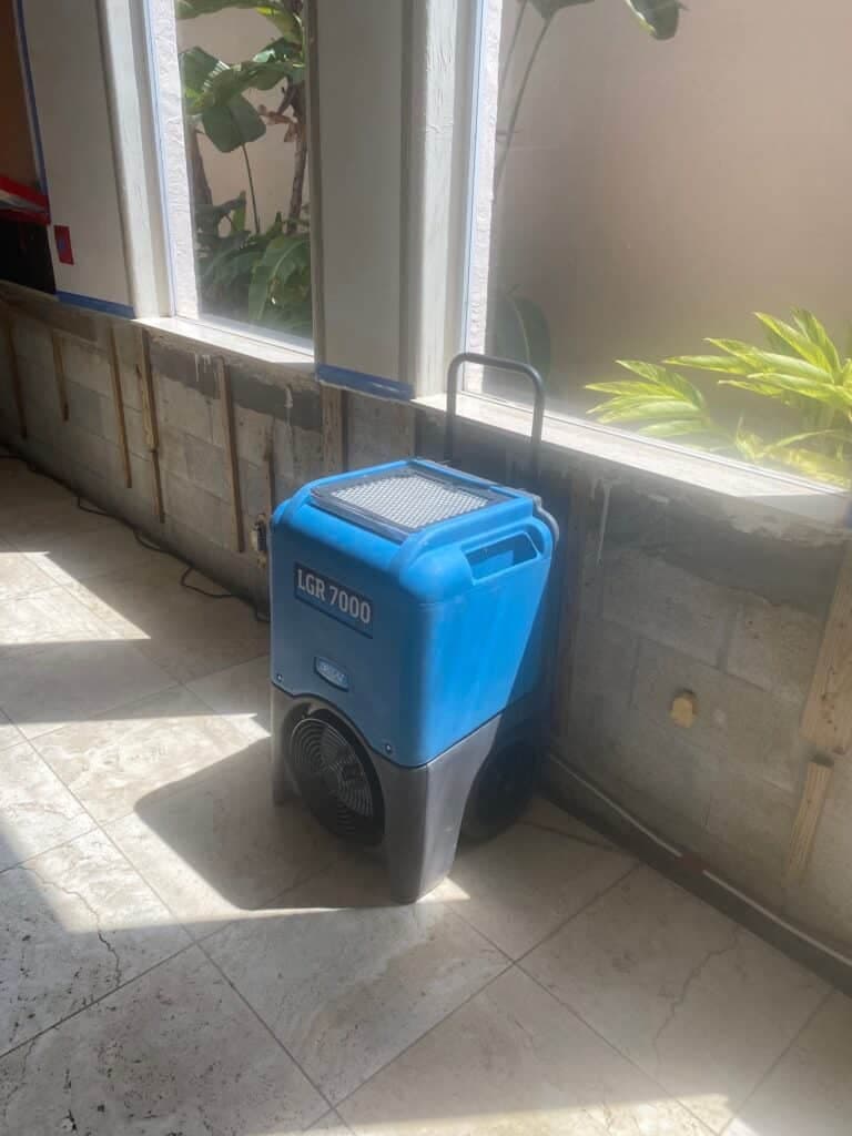 Commercial LGR dehumidifier drying a flood-cut wall